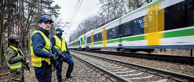 AFP 연합뉴스러 배후 의심… 철도 파괴후 보안 강화한 폴란드   지난달 27일 폴란드 수도 바르샤바 외곽을 달리는 열차를 철도 보안 요원 두 명과 무장한 국토방위군이 바라보고 있다. 폴란드는 지난달 철도 파괴와 화재 등 사건 배후에 러시아가 있다고 보고 있다.
