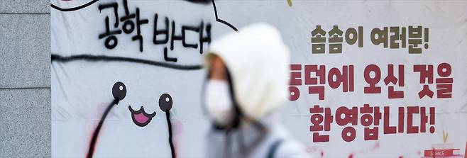 3일 서울 성북구 동덕여대 건물에 붙어있는 ‘공학 반대’ 현수막 앞을 한 학생이 지나가는 모습. 이날 동덕여대는 2029년부터 남녀 공학으로 전환한다고 밝혔다./뉴시스