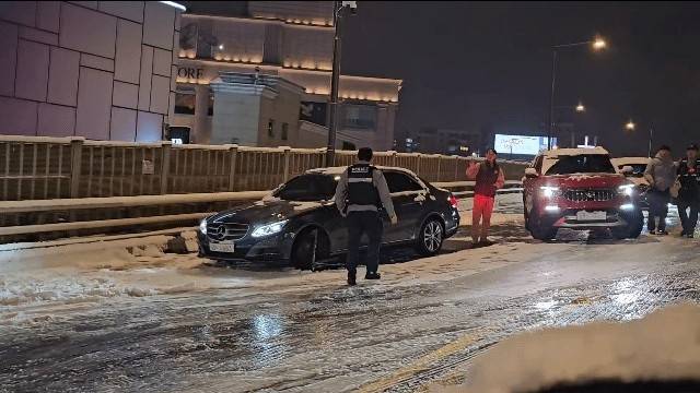 A vehicle comes to a stop on an icy overpass near Dongho Bridge in Apgujeong, southern Seoul, on Thursday. (Yonhap)