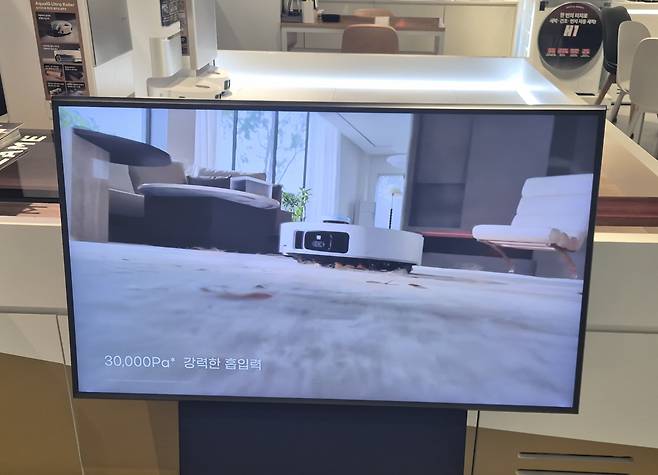 A robot vacuum cleaner promotes its 30,000 pascals (Pa) suction power in a video ad played inside an electronics store in Songpa District, southern Seoul, on Dec. 2. [YI WOO-LIM]