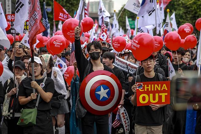 Protesters march toward Gwanghwamun holding signs and flags during an anti-government rally organized by the far-right group Freedom University near Dongdaemun Station in Seoul on Oct. 3, with one participant displaying a placard that reads “China Out.” (Newsis)