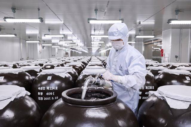 화요 관계자가 경기 여주시 제2공장에서 두 차례 증류를 마친 소주 원액이 담긴 옹기를 검수하고 있다. 전통적 방식으로 제작된 옹기에서 약 3개월의 숙성 공정을 거친다. 화요 제공