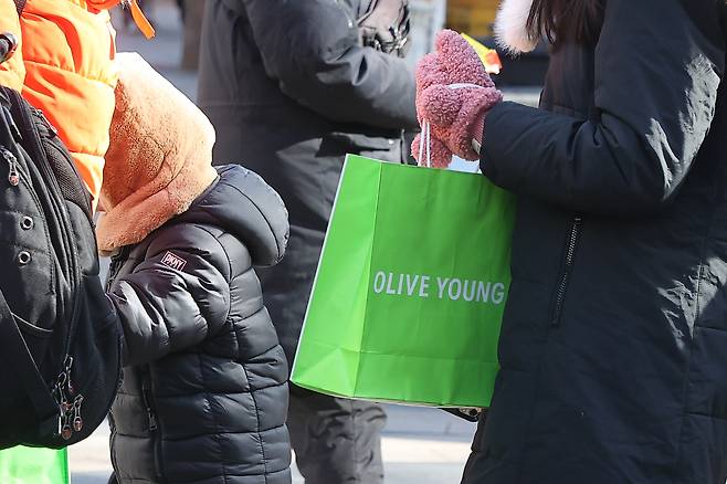 People carrying Olive Young shopping bags are seen on a street in central Seoul on Jan. 9. [YONHAP]