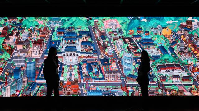 일제강점기를 거치지 않고 부국강병을 이룬 서울의 모습을 쿠키런 그림체로 그린 ‘꺼지지 않을 희망의 빛’ 미디어아트를 관람객들이 살펴보고 있다. 가운데 경복궁과 창덕궁 등이 보인다. 연합뉴스