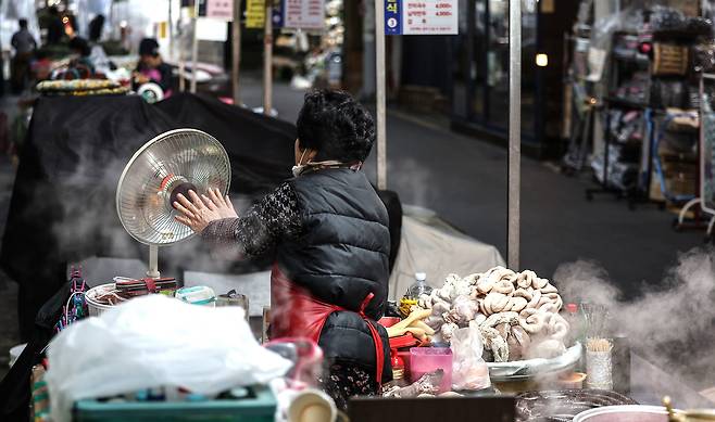 이재명 대통령 취임 6개월 동안 빈부격차는 더 커지고 물가가 올라 서민들의 생활이 더 팍팍해졌다. 사진은 지난 12월 3일 대구 중구 서문시장에서 한 상인이 추위에 언 손을 난방기에 녹이는 모습./연합뉴스