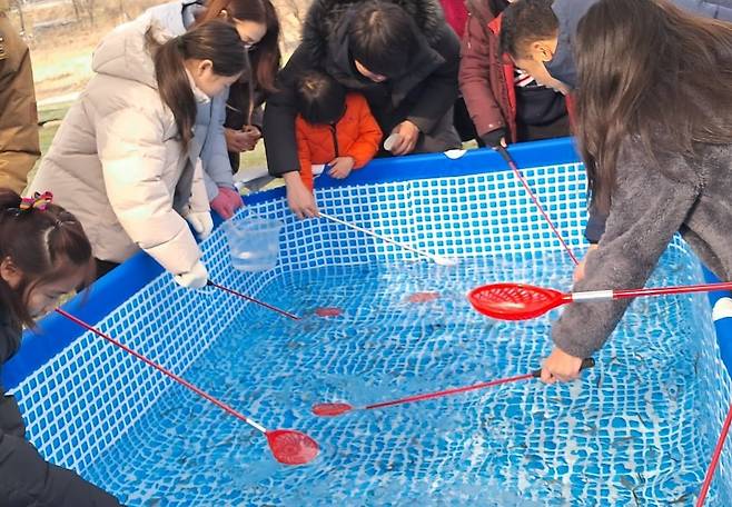 양평빙송어축제에서 뜰채로 빙어를 낚고 있는 관람객들. /수미마을