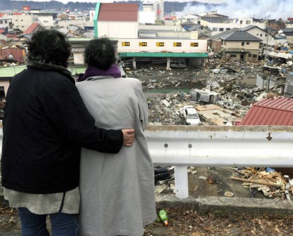 동일본 대지진이 발생한 직후인 지난 2011년 3월 15일 일본 미야기현 게센누마에서 이재민들이 폐허 속에 묻힌 자신의 집을 바라보는 모습. [사진=교도/연합뉴스]