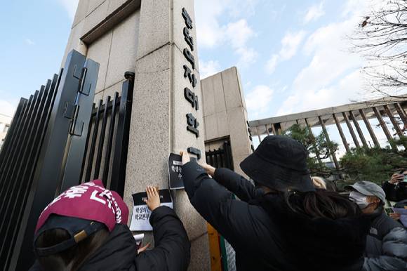 지난 9일 서울 성북구 동덕여자대학교 정문에서 열린 '2025 학생총투표 결과 전달 기자회견'에서 학생들이 공학 전환에 반대하는 내용의 손팻말을 교문에 붙이고 있다. [사진=연합뉴스]