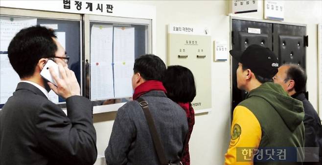 경매 투자자들이 법원 게시판에 나온 매물 정보를 살펴보고 있다. 사진=한경DB