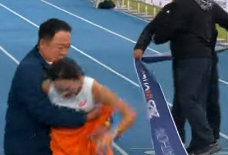 인천 국제마라톤 현장에서 삼척시청 김완기 감독이 1위로 결승선에 들어오고 있는 이수민 선수를 잡아주고 있다. (사진=KBS)