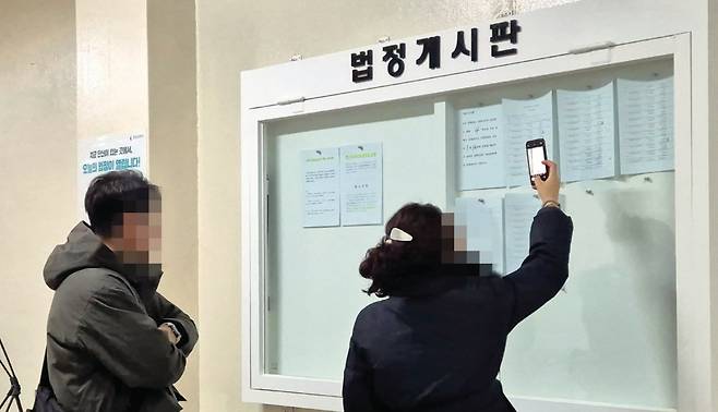 12월 3일 오전 서울중앙지법에서 매각기일 공고를 보고 있는 응찰자들. 윤채원 기자