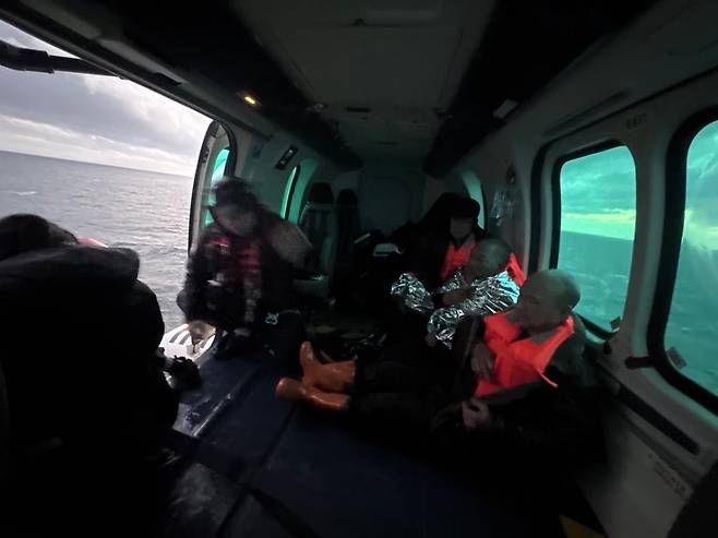 Crew members who fell overboard from a cargo ship off the southern coast of Seogwipo, Jeju, are seen inside a helicopter after being rescued by the Seogwipo Coast Guard on Dec. 12. [SEOGWIPO COAST GUARD]