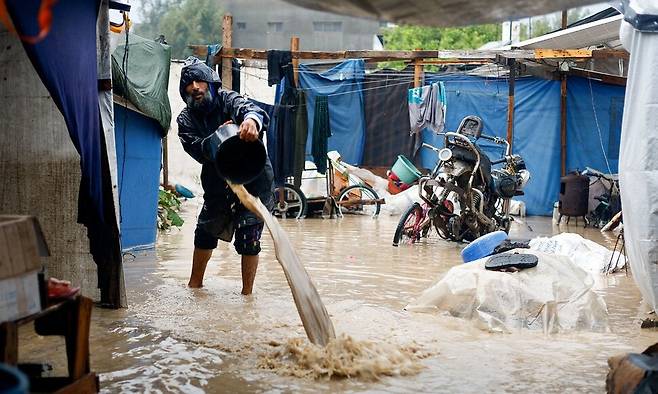 12일(현지시각) 팔레스타인 가자지구 중부 누사이라트 난민캠프에서 한 팔레스타인 주민이 물을 퍼내고 있다. 로이터 연합뉴스