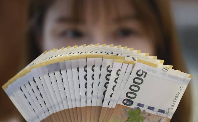 A Hana Bank employee holds 50,000 won bills at the bank’s headquarters in central Seoul. (Newsis)