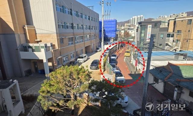 광주시 경안동 광주초등학교 후문 앞 막다른 통학로. 븕은색 포장도로 학교담장 옆으로 차량 여러대가 주차돼 있다. 이 도로는 어린이보호구역으로 지정되지 않아 사고 위험이 크지만 시와 학교 측은 책임공방을 벌이고 있어 대책 마련이 시급하다. 한상훈기자
