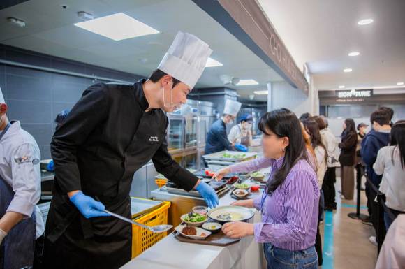 지난 3월 인천 송도에 위치한 포스코타워-송도 사내식당에서 열린 밋더셀럽 이벤트에서 최현석 셰프가 직접 배식을 하고 있다. [사진=아워홈]