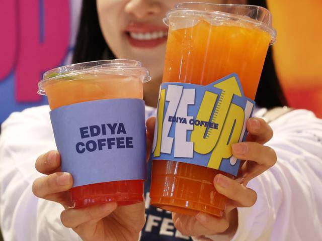 16일 서울 중구 이디야커피 IBK본점에서 모델이 음료 용량 확대 및 메뉴 라인업 개편을 알리는 '사이즈 업&라인 업' 행사를 홍보하고 있다. 왼쪽은 기존 이디야커피 기본 사이즈였던 14온스 용량, 오른쪽은 새로 추가한 엑스트라(EX) 사이즈다. 이디야커피는 이날부터 기존 14온스 중심의 용량 기준을 18온스로 전부 통일했다. 연합뉴스