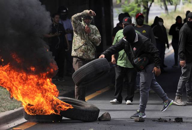 15일 온두라스 테구시갈파에서 대선 개표 지연과 부정 의혹에 항의하는 시위가 이어지는 가운데 한 시위대가 불타는 바리케이드에 타이어를 올리고 있다. 로이터 연합뉴스