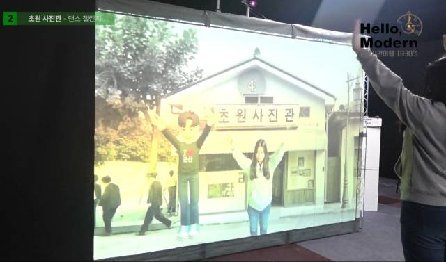 ▲ AI-XR ‘시간여행사진관’ 체험 장면. 관람객의 동작을 인식해 1930년대 군산 초원사진관을 배경으로 3D 캐릭터가 함께 움직이는 ‘댄스 챌린지’ 콘텐츠가 구현되고 있다. ⓒ프레시안