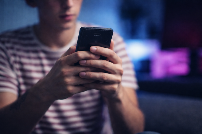 스마트폰을 손에 쥔 10대 남성의 모습. 전문가들은 암호화폐를 결제 수단으로 한 온라인 카지노가 규제 사각지대에서 청소년·청년층을 빠르게 끌어들이고 있다고 경고한다. 자료사진