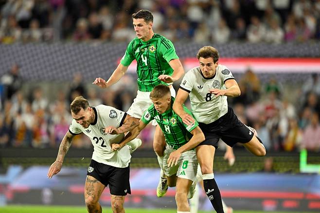 지난 9월8일 독일 쾰른에서 열린 북중미 월드컵 예선에서 독일과 북아일랜드 축구대표팀 선수들이 몸싸움을 벌이고 있다. 축구 국가대표팀 경기부터 고대 제국의 전쟁에 이르기까지 고통을 함께하는 집단적 유대감의 경험은 오래전부터 사회를 묶는 데 사용된 부족주의 메커니즘이다. AFP연합뉴스