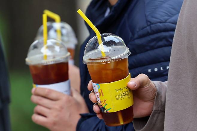 Two people hold disposable cups in Seoul on Oct. 13, 2023. [NEWS1]