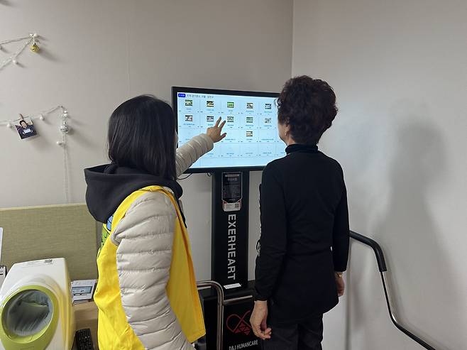 Kang Gil-ja, a Yangcheon resident, uses a walking exercise machine at a smart senior center in western Seoul on Nov. 4, as a staff member assists her in selecting a program. [CHO JUNG-WOO]