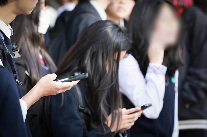Students look into their smartphones at a school in Seoul on Nov. 4, 2024. [YONHAP]