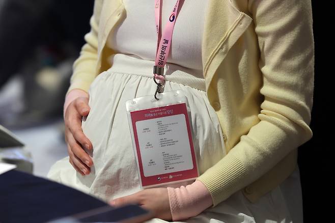 A pregnant woman touches her belly during an event for pregnant women held in Seoul in October. [NEWS1]
