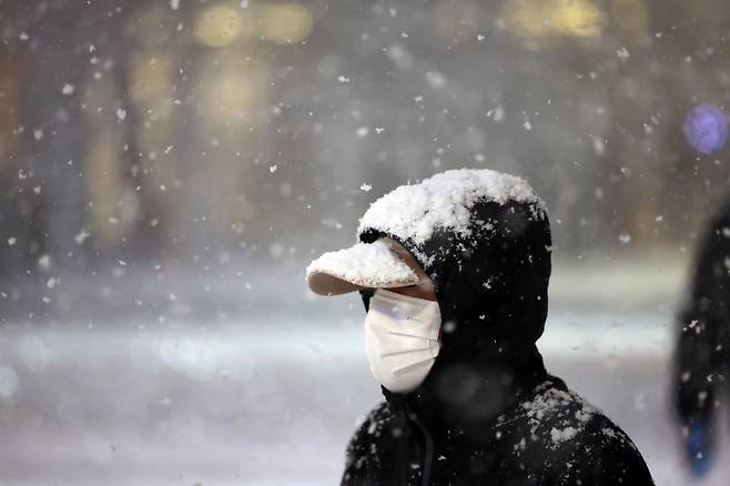 A pedestrian walks through snow at the Gwanghwamun intersection in central Seoul on Dec. 4. [NEWS1]