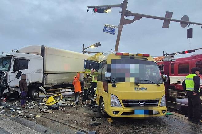 23일 오후 4시26분쯤 전북 김제시 백산면 상정리 지평선산단로 돌제교차로에서 초등학교 스쿨버스가 화물 윙바디 트럭과 충돌한 뒤 안전지대에 세워진 신호등과 추돌하는 사고가 나자 119 구급대원들이 분주하게 구조하고 있다. 전북도소방본부 제공