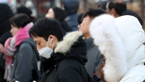 People clad in thick coats, mufflers and gloves walk on a street near Gwanghwamun Square in Jongno District, central Seoul on Dec. 12. [NEWS1]