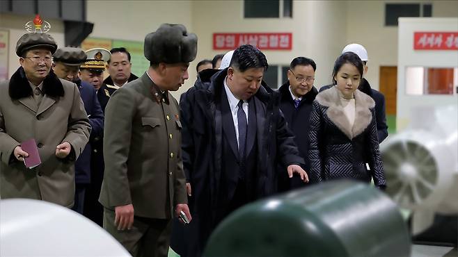North Korean leader Kim Jong-un, center, tours a weapons facility with his daughter, Kim Ju-ae, right of center, in this photo released by the Korean Central News Agency on Dec. 24. [KOREAN CENTRAL NEWS AGENCY]