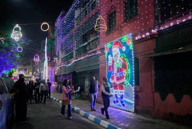 23일 인도 콜카타의 보우 배럭 주택가에서 시민과 관광객들이 크리스마스 장식이 된 거리를 거닐고 있다. 콜카타=AP/뉴시스