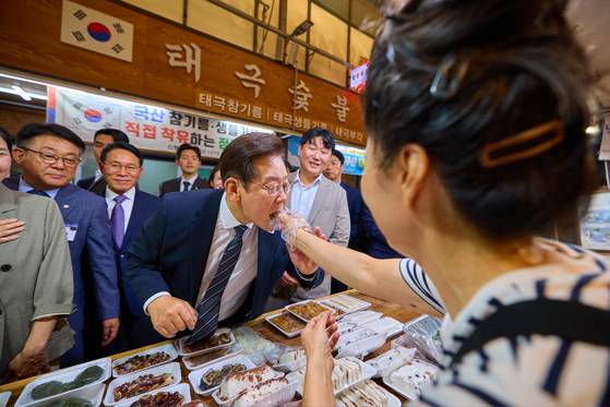 이재명 대통령이 지난 9월 5일 인천 미추홀구 용현시장을 방문해 한 상인이 건네는 음식을 맛보고 있다. 사진 대통령실