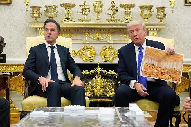 트럼프 대통령이 지난 10월 마크 뤼터 북대서양조약기구(나토) 사무총장과의 백악관 정상회담 도중 백악관 연회장 조감도를 꺼내들어 설명하고 있다. 워싱턴=AP 뉴시스