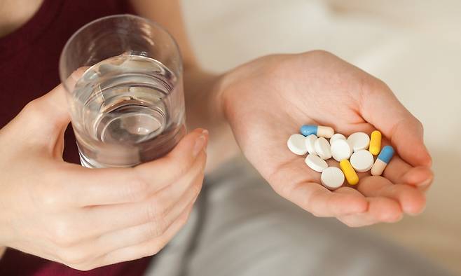 물 한 컵과 여러 알의 영양제를 함께 들고 있는 모습. 게티이미지뱅크