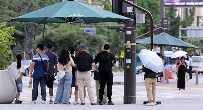 광화문네거리에서 시민들이 횡단보도 앞 그늘막 아래 모여 신호를 기다리고 있다. 2025.8.21 뉴스1