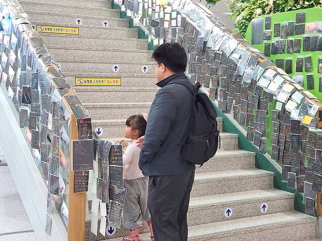 28일 오후 어린 딸과 함께 무안공항을 찾은 한 추모객이 1층 ㄴ나간에서 2층으로 이어지는 추모의 계단 앞에서 발길을 멈추고 편지를 읽고 있다. ⓒ시사저널 정성환