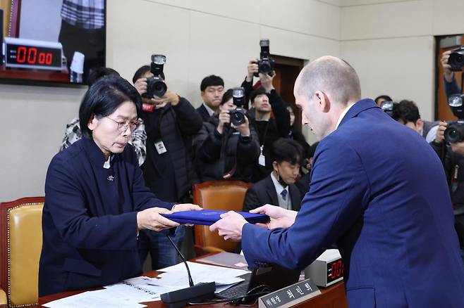 해롤드 로저스 쿠팡 임시대표가 30일 서울 여의도 국회에서 열린 제430회국회(임시회) 쿠팡 침해사고 및 개인정보 유출, 불공정 거래, 노동환경 실태 파악과 재발방지 대책 마련을 위한 연석 청문회에 출석해 선서문을 최민희 위원장에게 전달하고 있다. 2025.12.30 뉴스1