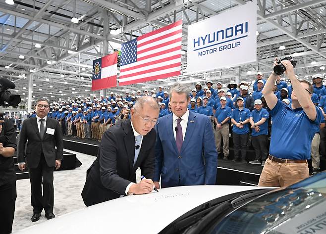 Hyundai Motor Group Executive Chair Chung Euisun (center, left) signs an Ioniq 5 electric vehicle at the completion ceremony of Hyundai Motor Group Metaplant America in Georgia in March. Georgia Gov. Brian Kemp stands to his left. (Hyundai Motor Group)