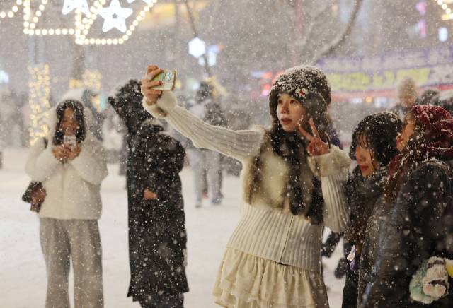 4일 서울 마포구 홍대 부근에 눈이 내리는 가운데 외국인 관광객들이 기념사진을 촬영하고 있다. 연합뉴스