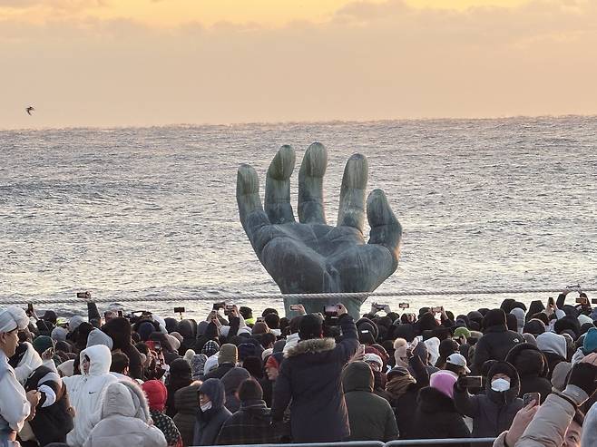 2026년 병오년(丙午年) 새해 첫날인 1일 포항 호미곶 해맞이광장에서 시민과 관광객들이 ‘상생의 손’ 뒤로 떠오르는 해를 휴대전화에 담고 있다.