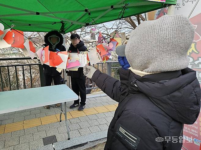 2026년 병오년(丙午年) 첫날인 1일 오전 8시께 광주 남구 월산근린공원 정상에서 해맞이 행사가 열린 가운데, 한 시민이 새해 소망 카드를 보고 있다. 강주비 기자