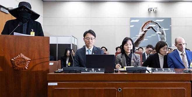 얼굴 가리고 쿠팡 갑질 증언하는 소상공인 31일 국회 쿠팡 청문회에서 선글라스와 마스크 등으로 얼굴을 가린 소상공인(맨 왼쪽)이 참고인으로 출석해 쿠팡의 횡포 등에 대해 진술하고 있다. 해롤드 로저스 쿠팡 임시 대표(가장 오른쪽)는 통역사의 도움을 받아 해당 소상공인의 발언을 들었다./뉴스1