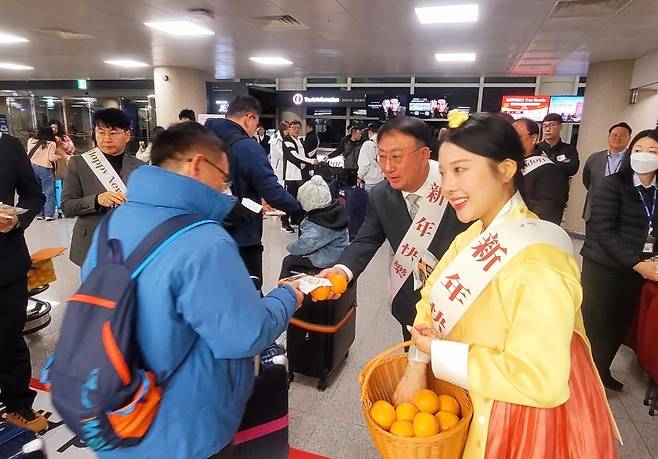 제주국제공항에서 새해 첫날 방문객에게 감귤과 기념품을 전달하고 있다. (제주도관광협회 제공)