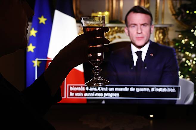 지난 12월 31일(현지시간) 에마뉘엘 마크롱 프랑스 대통령의&nbsp;대국민 연설을&nbsp;TV로 지켜보던 어느 시민이 술잔을 들어올리고 있다. 마치 최악의 정치적 위기에 놓인 마크롱을 위한 건배 제의처럼 보인다. EPA연합뉴스