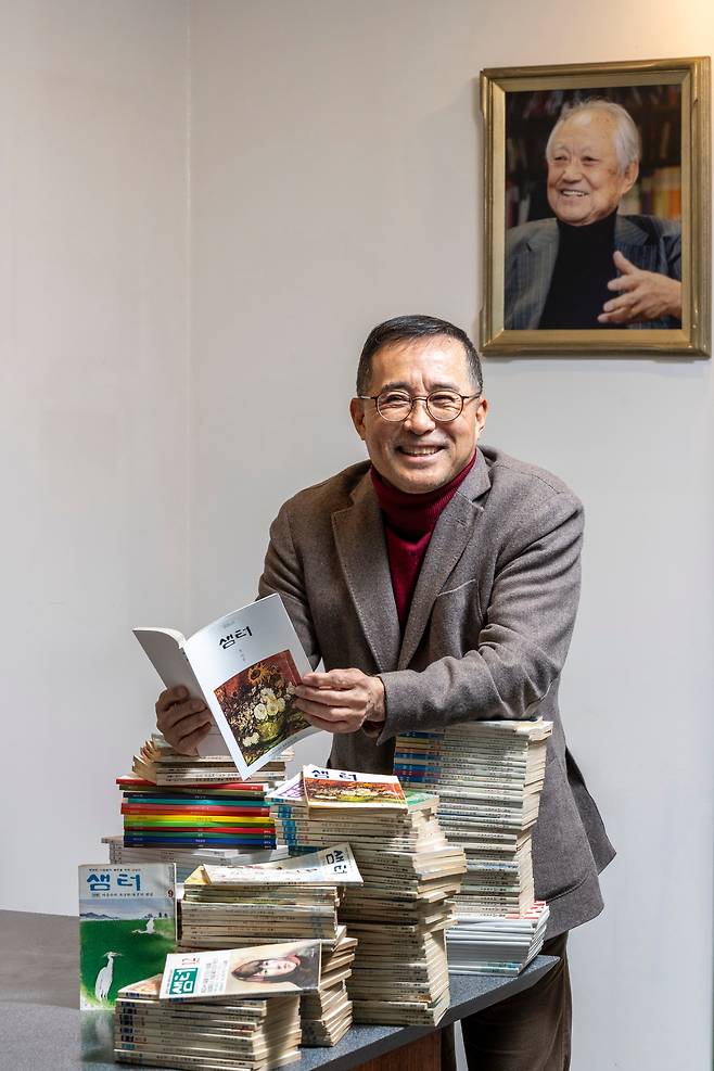 김성구 월간 ‘샘터’ 발행인이 자신의 사무실에서 한동안 최신호로 남을 샘터 2026년 1월호를 들어 보이고 있다. ‘첫마음’을 주제로 한 이번 호에 고명재 시인이 기고한 글엔 이런 대목이 있다. “우리는 의지만 있다면 언제든 처음을 만들고 처음 속으로 들어갈 수 있다. (중략) 사랑한다는 건 처음을 발굴하는 일. 모든 일이 끝났다 해도 다시 새잡이하는 일. 새해에는 단단히 마음을 먹는다.” 김 발행인 뒤로 샘터 창간인인 김재순 전 국회의장의 사진이 보인다. /이신영 영상미디어 기자