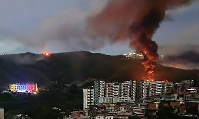 3일 베네수엘라 최대 군사 복합 단지인 푸에르테 티우나에서 화재가 발생한 모습이 멀리서 찍힌 모습이다. 이날 미군 특수부대가 카라카스에 진입해 일부 시설에 대한 공격을 하고 니콜라스 마두로 베네수엘라 대통령과 그의 부인을 체포해 압송했다고 도널드 트럼프 미국 대통령이 밝혔다. AFP 연합뉴스