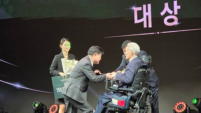 지난달 'HD현대 1% 나눔재단'의 아너상 시상식에서 장애가 있는 수상자에게 무릎을 꿇고 상패를 전달하고 있는 권오갑 명예회장(왼쪽). /HD현대 제공